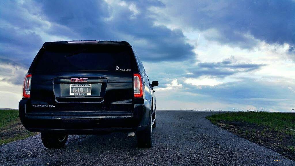 Picture of a GMC Yukon XL from the back with a scenic background while the sun is setting. 