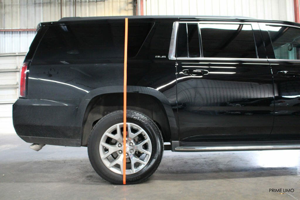Orange tape on the rear of a black Yukon XL  separating a very dirty and a very clean area