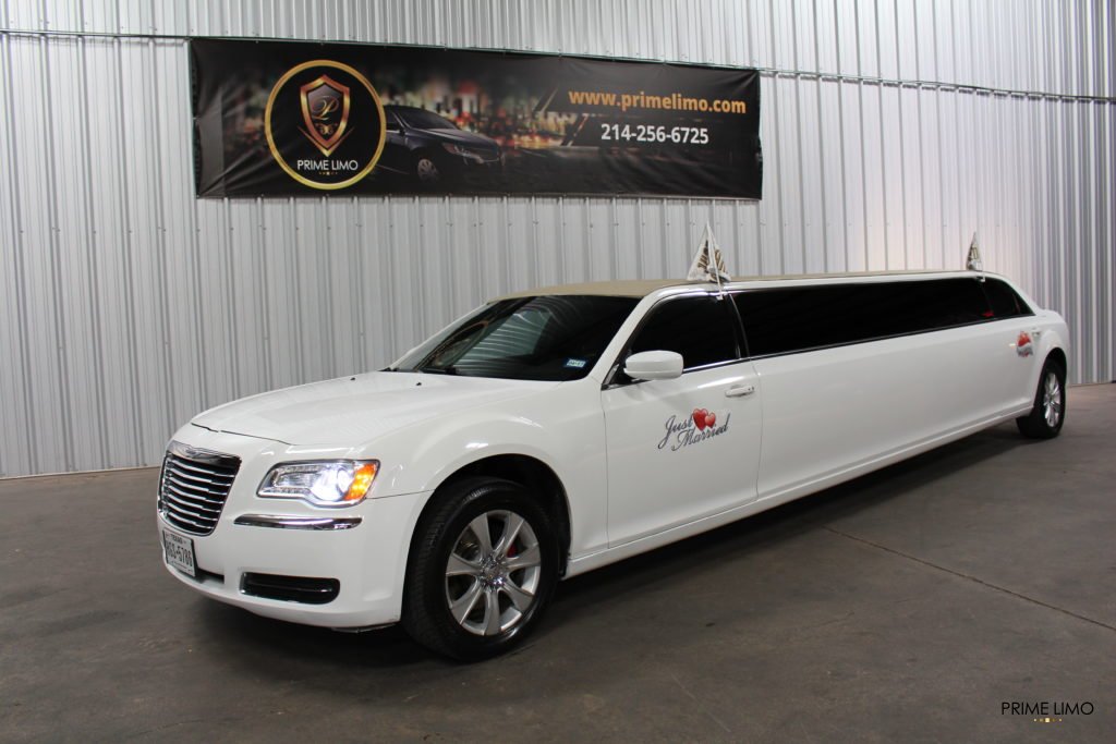 White Chrysler 300 limo with Just Married Signs and flags