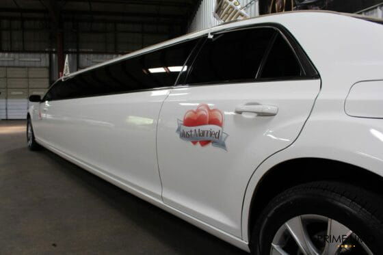 White Chrysler 300 limo with Just Married Signs and flags