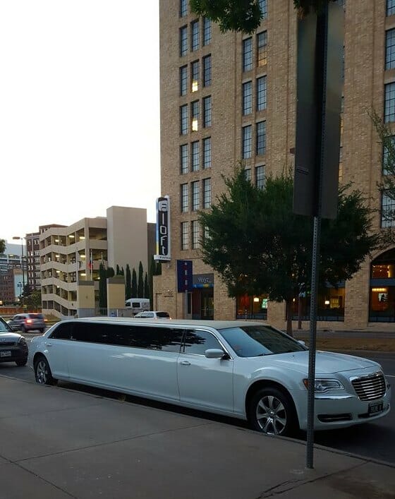 White Chrysler 300 limo outside Pioneer Plaza with building in the back during the day