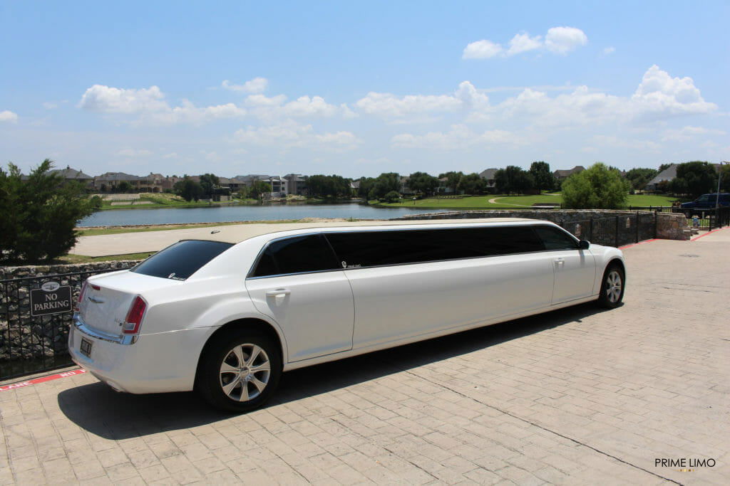 White Chrysler 300 limo in front of water on cloudy day
